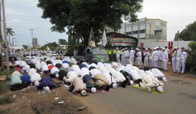 Para peserta aksi demo damai sedang melaksanakan Salat Asar di depan pintu gerbang proyek pembangunan gereja St Clara Bekasi. (HIDUP/A. Nendro Saputro).